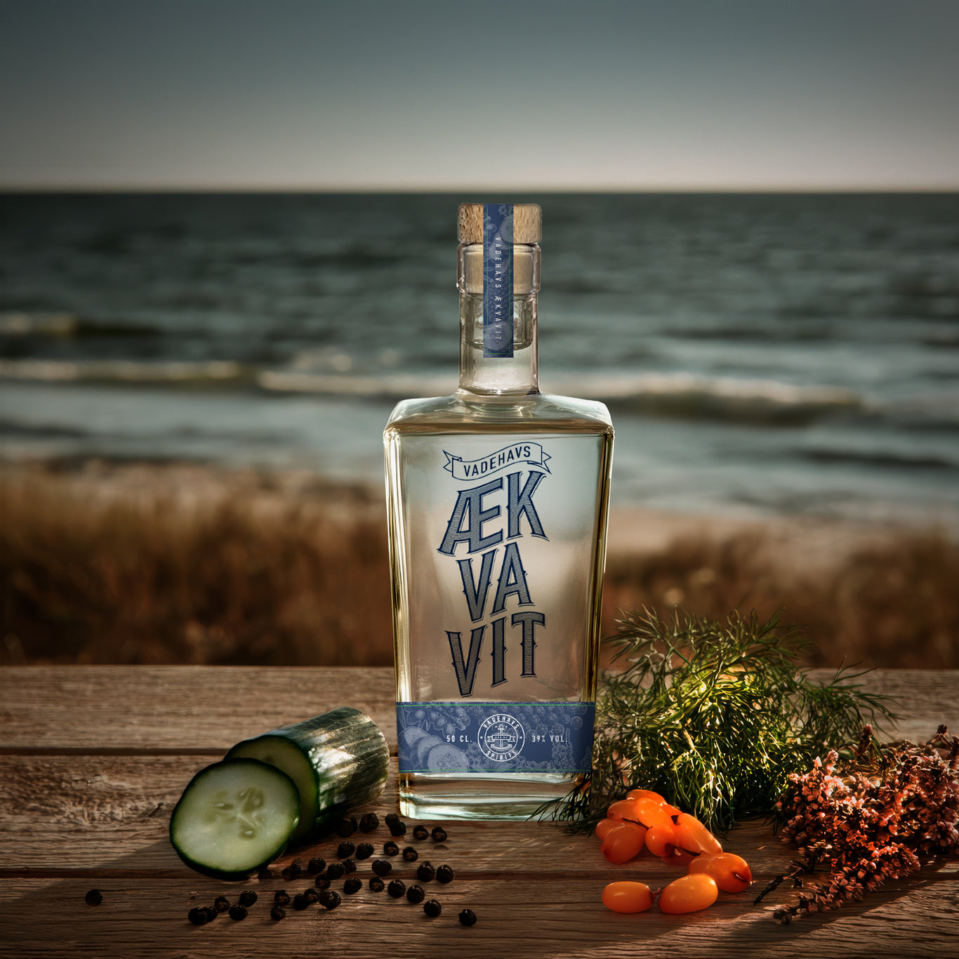 Vadehavs Ækvavit flaske med botanicals på træbord ved havet